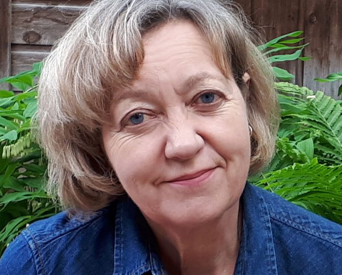 Paulette Blais, wearing a blue shirt, in her garden